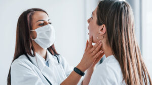 Fonoaudióloga examina a garganta de paciente durante a sessão