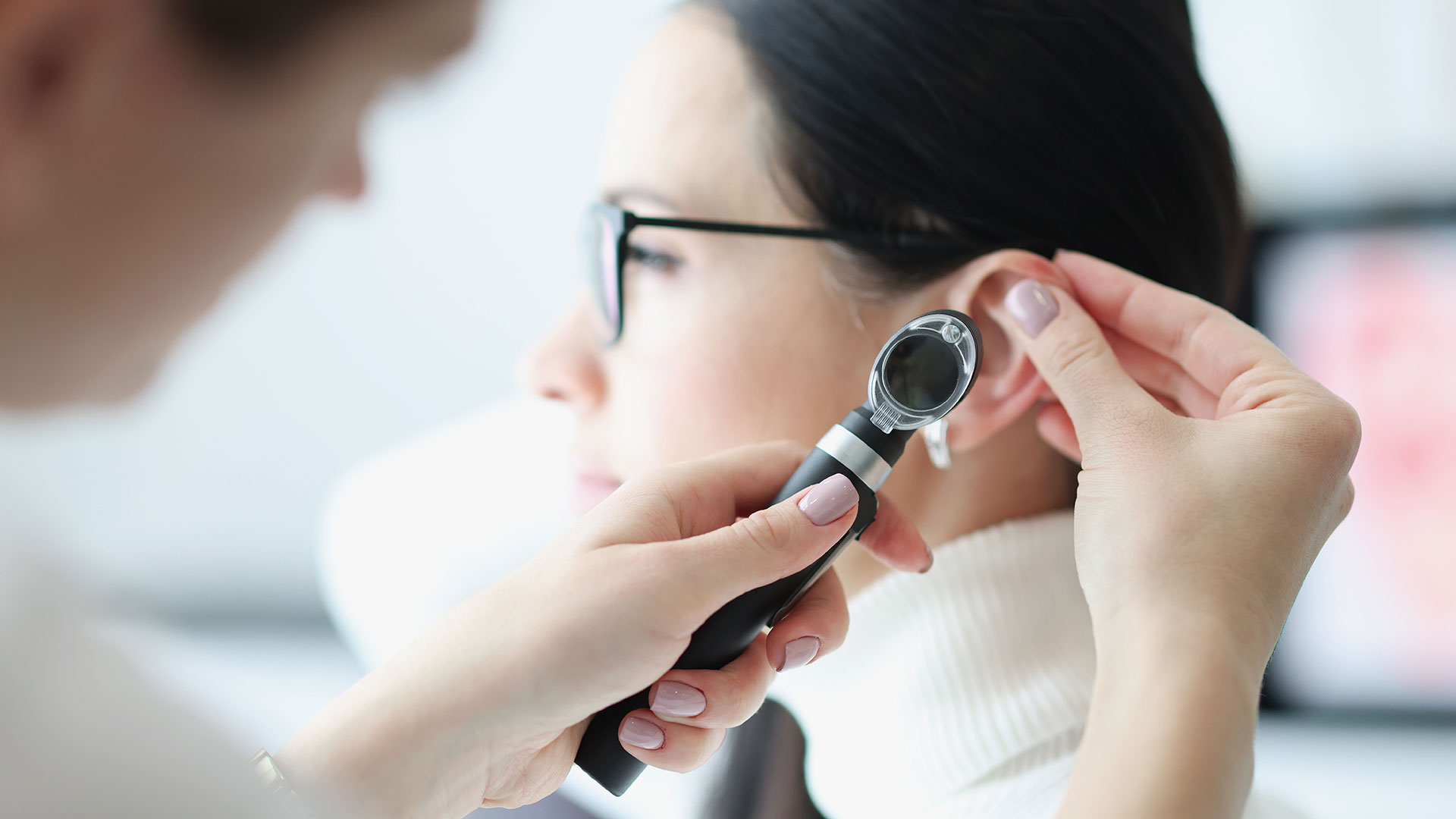 Médica otorrinolaringologista examina ouvido de paciente com instrumento